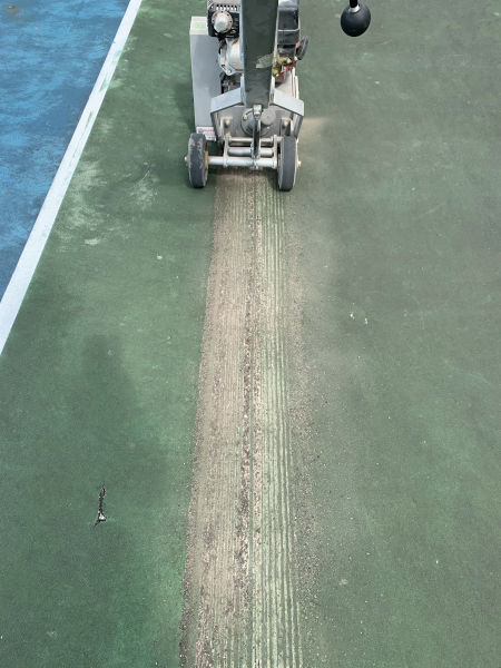 grinding cracks in tennis court getting ready for repair